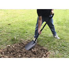 O persoană sapă în grădină cu o lopată.