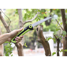 O mână ține un ferăstrău de ramuri în timp ce taie o ramură.