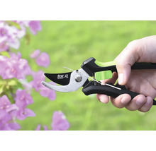 O foarfecă de grădină marca for.q într-o mână în fața florilor