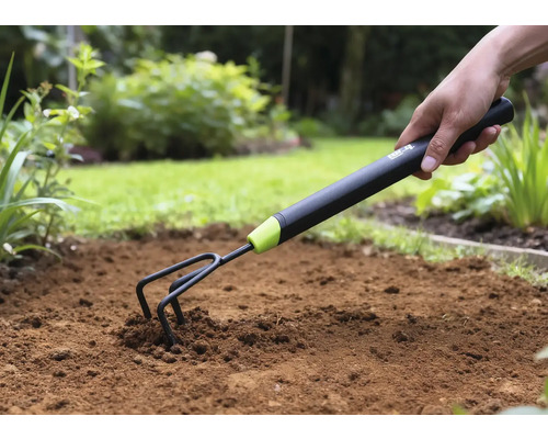 Prim-plan cu o mână care împinge o gheară de grădină în pământ