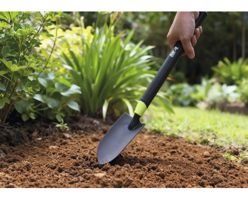 O persoană folosește o lopată de grădină într-un strat de grădină.