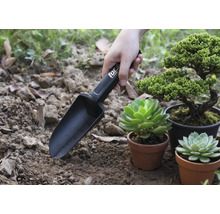 Lopată de grădină cu marcaje în uz lângă plante în ghivece.