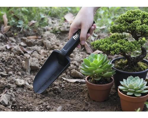 Lopată de grădină cu marcaje în uz lângă plante în ghivece.