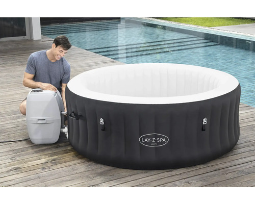 Cădiță gonflabilă cu hidromasaj Lay-Z-Spa Miami cu bărbat și pompă pe o terasă din lemn lângă o piscină
