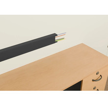 Canal de cabluri din plastic cu cabluri pe un perete deasupra unui birou