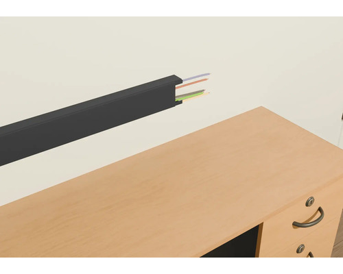 Canal de cabluri din plastic cu cabluri pe un perete deasupra unui birou