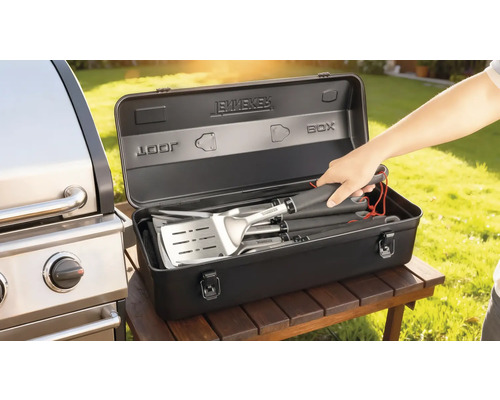 Set de ustensile pentru grătar într-o cutie de depozitare neagră lângă un grătar