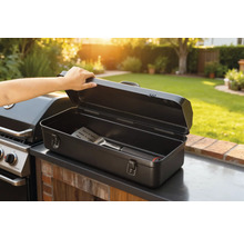 Cutie deschisă pentru ustensile de grătar cu spatulă lângă grătar în grădină.