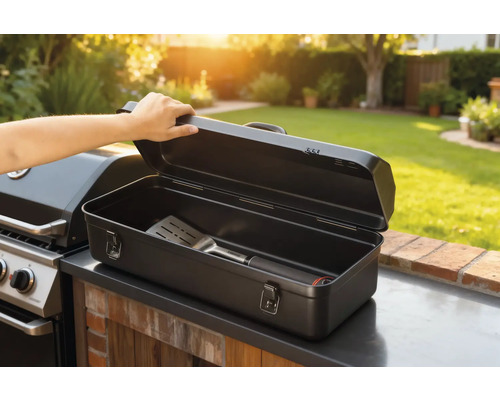 Cutie deschisă pentru ustensile de grătar cu spatulă lângă grătar în grădină.