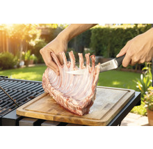 Prepararea cotletului de miel pe o scândură de lemn cu un cuțit Tenneker în grădină.