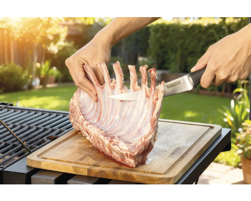 Prepararea cotletului de miel pe o scândură de lemn cu un cuțit Tenneker în grădină.