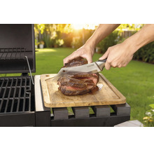 Friptura preparată este tăiată cu un cuțit pe o scândură de lemn lângă un grătar.