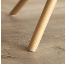 Prim-plan cu un picior de mobilă din lemn, cu protecție pentru podea.