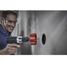 Un bărbat face o gaură într-un perete cu un ferăstrău circular