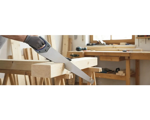 Un fierăstrău manual taie o bucată de lemn pe un banc de lucru.