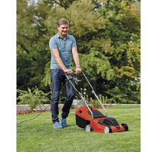 Un bărbat tunde gazonul cu o mașină de tuns iarba electrică.