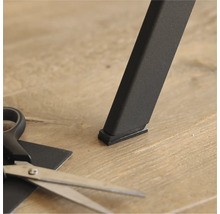 Glisor de mobilier sub un picior de masă și o foarfecă pentru tăiere la dimensiune