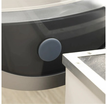 Detaliu al unei mașini de spălat cu un dop de închidere rotund, gri