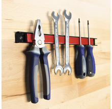 Unelte precum clește, chei și șurubelnițe pe o bară magnetică pentru scule.