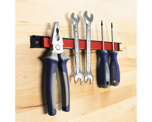 Unelte precum clește, chei și șurubelnițe pe o bară magnetică pentru scule.