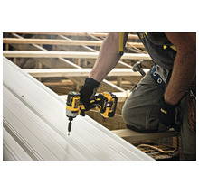 Un meseriaș fixează o placă metalică cu o șurubelniță cu impact cu acumulator Dewalt.