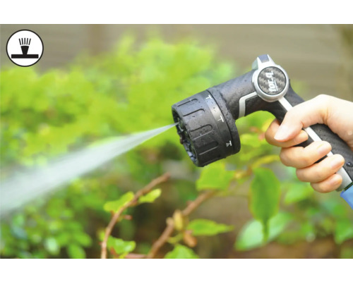 Mână ținând pistolul de pulverizare al furtunului de grădină în timp ce udă plantele