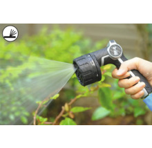 O persoană ține un pistol de pulverizare pentru grădină care pulverizează apă