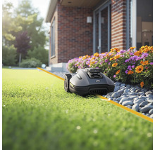 Robot de tuns iarba pe gazon în fața casei