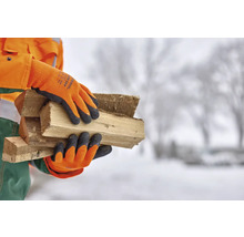 Persoană cu mănuși de lucru care transportă lemne de foc