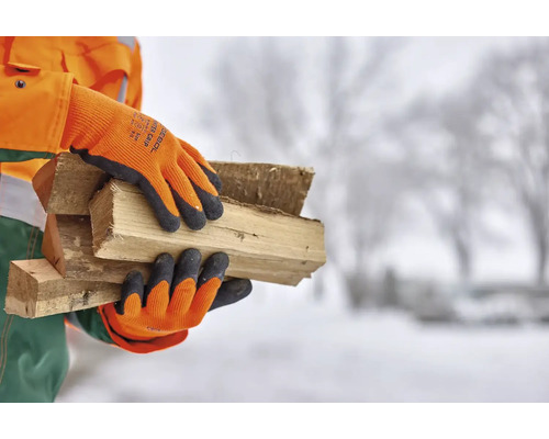 Persoană cu mănuși de lucru care transportă lemne de foc