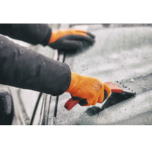 Persoană cu mănuși care folosește o racletă de gheață pe un parbriz