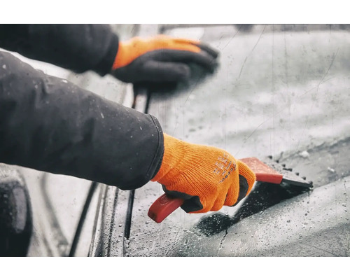 Persoană cu mănuși care folosește o racletă de gheață pe un parbriz