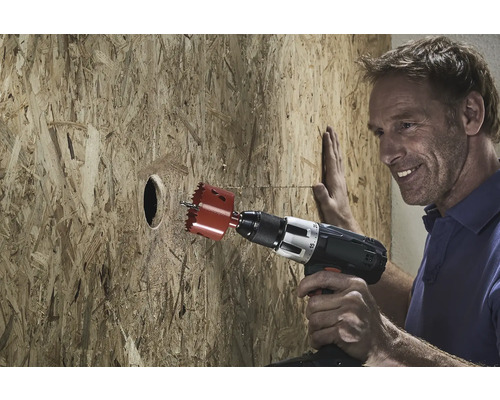 Bărbat care găurește o placă de lemn cu un ferăstrău circular.