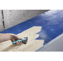 O persoană folosește un distribuitor de vopsea pentru a aplica vopsea pe lemn