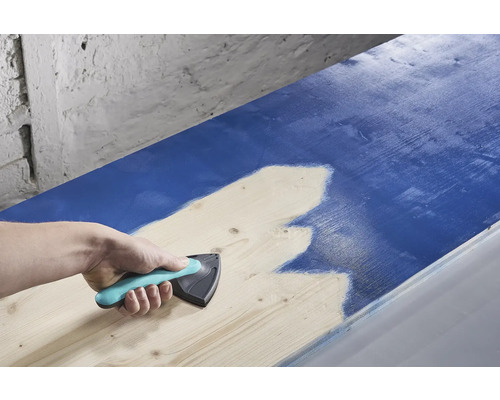 O persoană folosește un distribuitor de vopsea pentru a aplica vopsea pe lemn