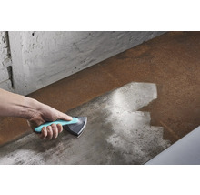 Mână cu racletă triunghiulară care curăță o suprafață metalică