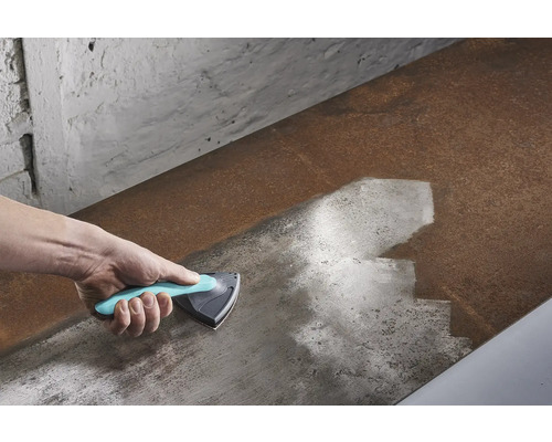 Mână cu racletă triunghiulară care curăță o suprafață metalică