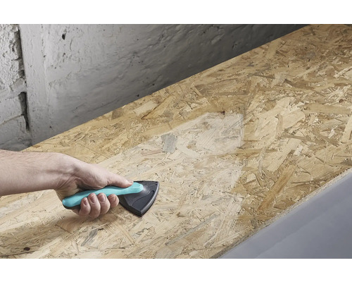 O mână ține un bloc de șlefuit și șlefuiește o scândură de lemn.