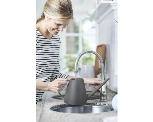 Femeie umplând o stropitoare gri la un robinet