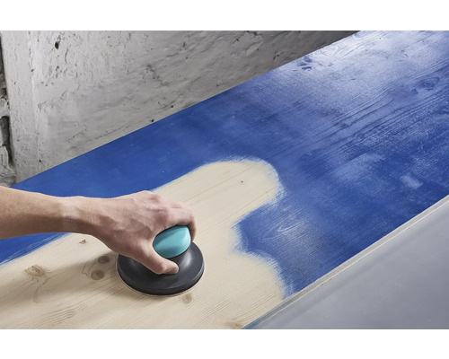 O persoană șlefuiește o suprafață de lemn albastră cu un șlefuitor excentric.