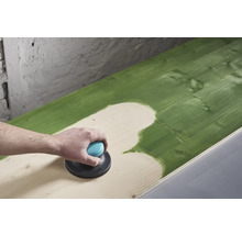 O persoană șlefuiește o suprafață de lemn vopsită în verde cu un șlefuitor excentric.