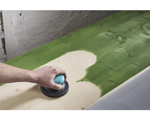 O persoană șlefuiește o suprafață de lemn vopsită în verde cu un șlefuitor excentric.