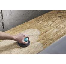 O persoană șlefuiește o placă de lemn cu o mașină de șlefuit manuală.