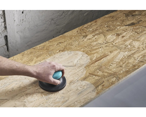 O persoană șlefuiește o placă de lemn cu o mașină de șlefuit manuală.