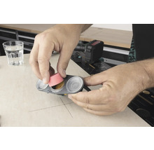 Un bărbat introduce un accesoriu de șlefuit într-un recipient cu vopsea.