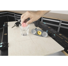 Scenă a unui banc de lucru cu o mașină de găurit, pahar cu apă și instrument de găurit faianță