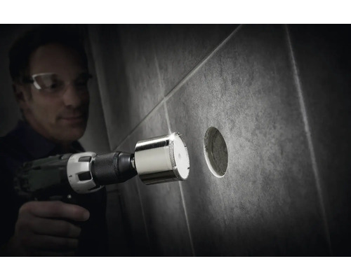 Bărbat găurind o gaură într-o faianță cu un burghiu diamantat.