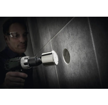 Bărbat găurind o gaură într-o faianță cu un burghiu diamantat.