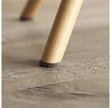 Prim-plan cu picior de scaun cu protecție din pâslă pe podea de lemn