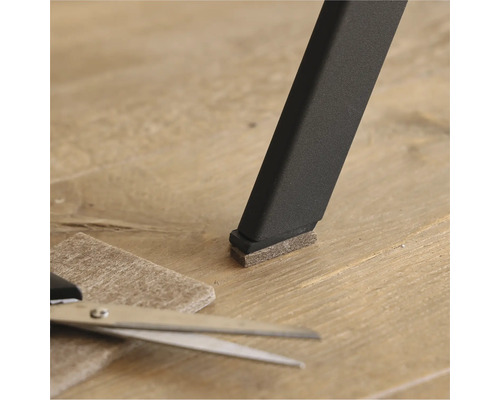 Glisor din pâslă pe un picior de scaun cu foarfecă și bucată de pâslă pe podea